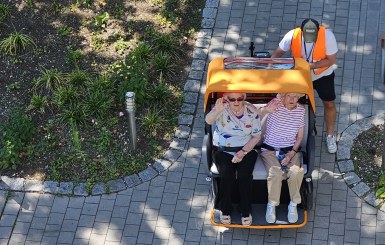 Auf dem Bild sitzen zwei Damen in der Rikscha und der Fahrer steigt auf.
