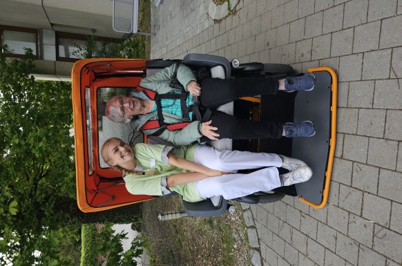 Auf dem Bild ist die Rikscha von der Bürgerstiftung FFB zu sehen. In der Rikscha sitzt eine Bewohnerin zusammen mit einer FOS Schülerin.
