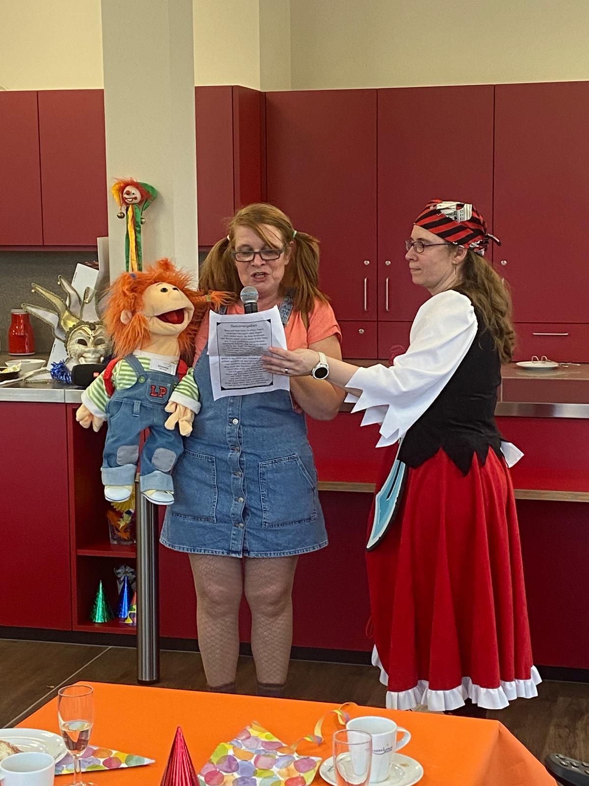 Dieses Bild entstand bei der Faschingsfeier. Es zeigt Karin Jansen mit Charlotta (Therapiepuppe) und Frau Menzel beim Vortragen der Büttenrede.