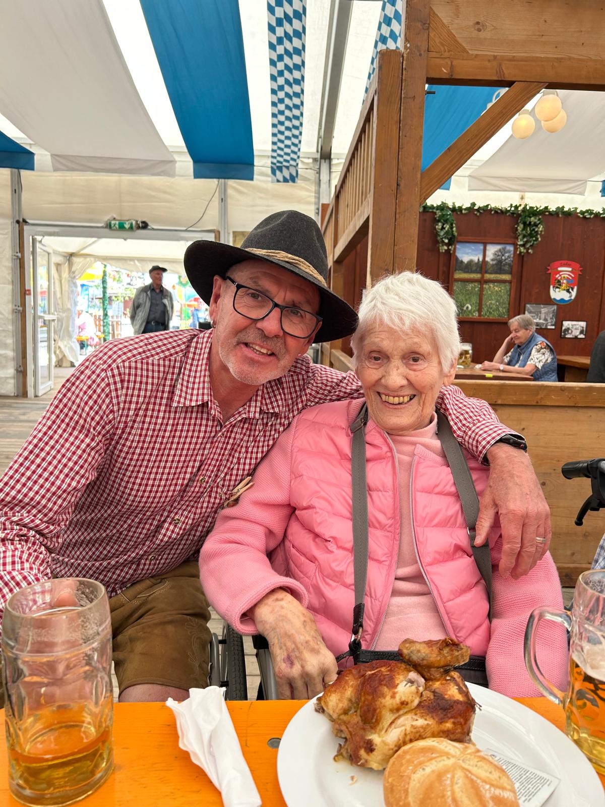 Auf dem Bild sitzen  unser Geschäftsführer Herr Seefried mit einer Bewohnerin vor Hendl und Bier zusammen.